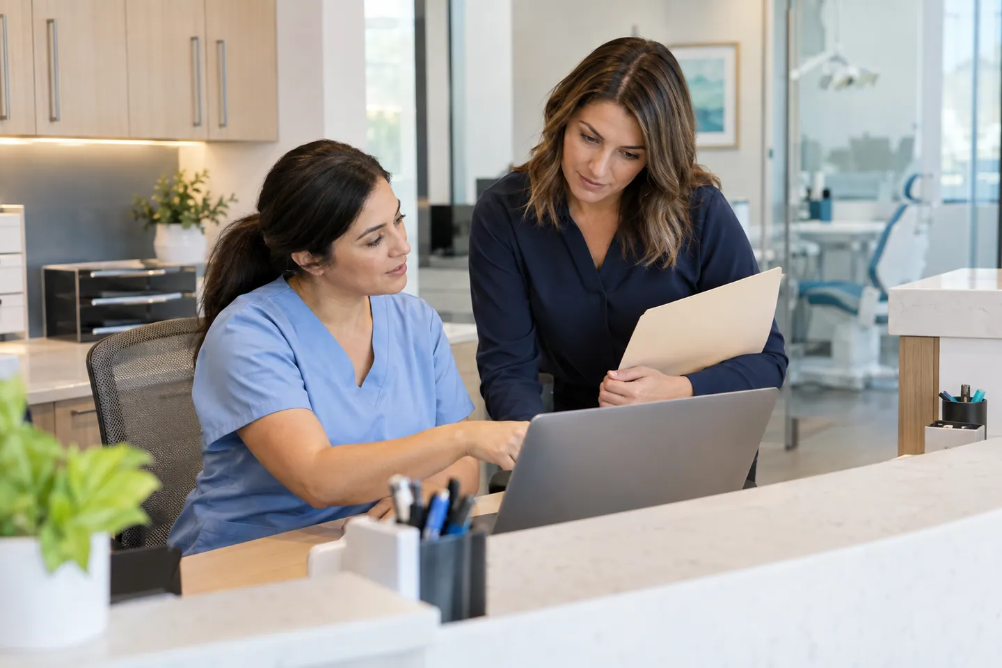 Dental office colleagues reviewing a laptop and paperwork together.