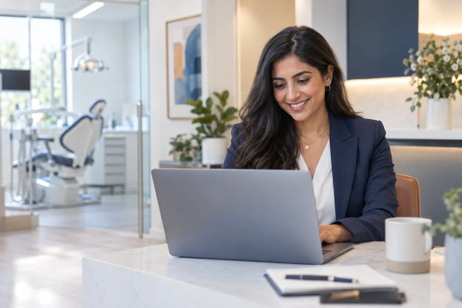dental practice manager working at a laptop in a bright office
