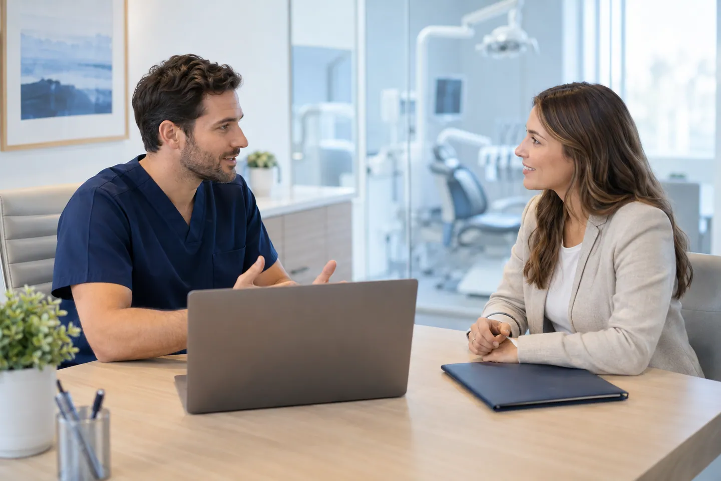 Dental provider and practice team member discussing onboarding beside a laptop.